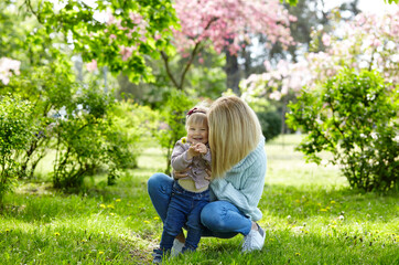Fototapeta premium Mom and daughter on nature walk at spring park. Little girl and mother have a good time on weekend activity