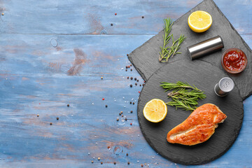 Board with tasty chicken fillet on color wooden background