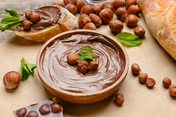 Bowl with tasty chocolate paste and hazelnuts on parchment