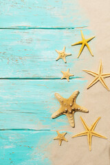Starfishes on a light blue wooden background with sand and copy space