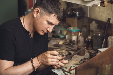 The jeweler inspects the gold ring for defects in his workshop