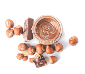 Jar with tasty chocolate paste and hazelnuts on white background