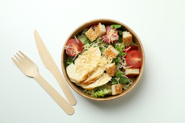 Bowl with Caesar salad and cutlery on white background