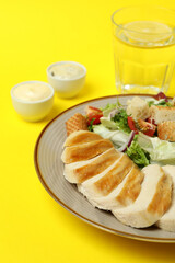Concept of tasty eating with Caesar salad on yellow background