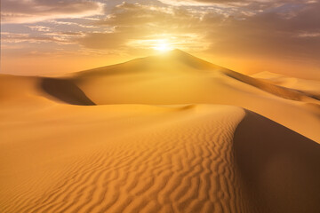 Obraz na płótnie Canvas Sunset over the sand dunes in the desert. Arid landscape of the Sahara desert.
