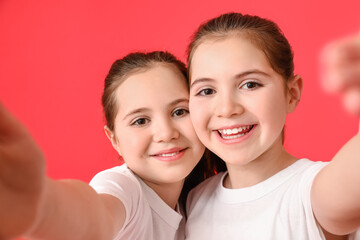 Cute twin girls taking selfie on color background
