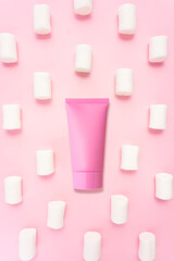 Creative beauty fashion concept photo of cosmetic recyclable bottle lotion cream with marshmallow candy on pink background.
