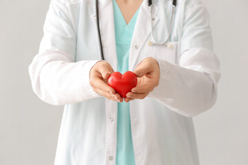 Female cardiologist with red heart on grey background