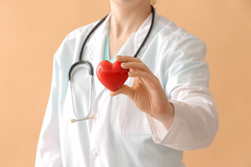 Female cardiologist with red heart on color background