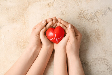 Hands of woman and child with red heart on grunge background