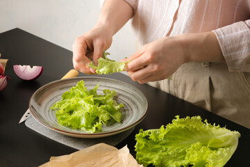 Woman preparing tasty Greek salad on table
