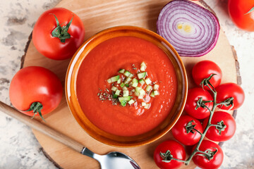 Bowl with tasty gazpacho and vegetables on light background