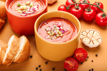 Bowls with tasty gazpacho on color background, closeup
