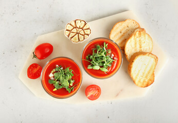 Glasses with tasty gazpacho on light background