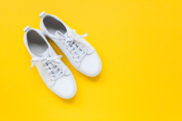 White leather sneakers with laces  on yellow background