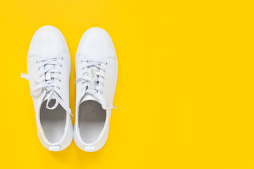 White leather sneakers with laces  on yellow background