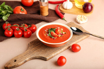 Bowl with tasty gazpacho and vegetables on color background