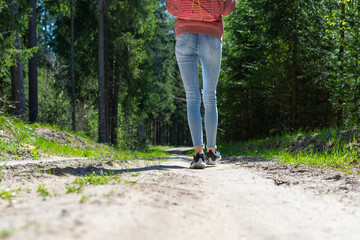 One Girl tourist with a backpack along the road in the woods.Summer warm day.Cropped image.