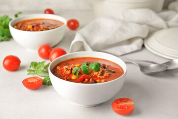 Bowls with delicious chili con carne on light background