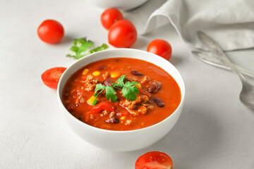 Bowl with delicious chili con carne on light background
