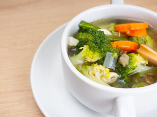 Vegetables soup that contain sausage, broccoli, carrots, etc on a white porcelain bowl