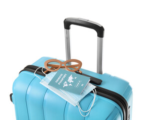 Packed suitcase with immune passport, medical masks and sunglasses on white background