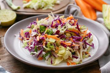 Plate with tasty cabbage salad on wooden table, closeup