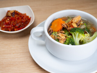 Vegetables soup that contain sausage, broccoli, carrots, etc on a white porcelain bowl
