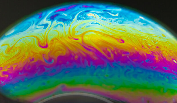 Vivid rainbow colours of a Macro soap bubbles creating psychedelic patterns under light dome