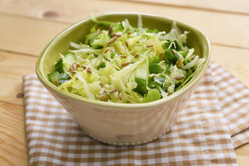 Bowl with tasty cabbage salad on wooden table