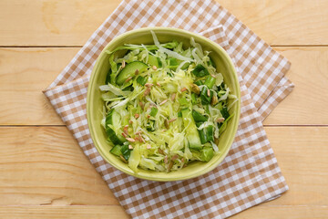 Bowl with tasty cabbage salad on wooden table