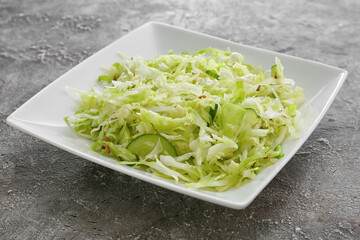 Plate with tasty cabbage salad on grunge background