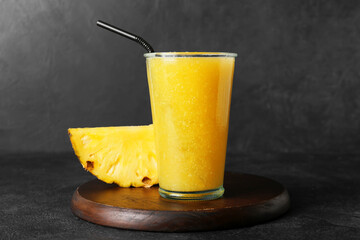 Glass of tasty pineapple smoothie on dark background