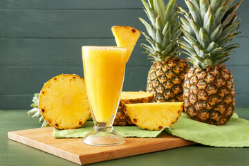 Glass of tasty pineapple smoothie on color wooden background