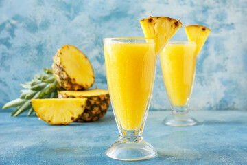 Glasses of tasty pineapple smoothie on color background
