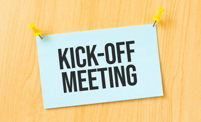 KICK-OFF MEETING sign written on sticky note pinned on wooden wall