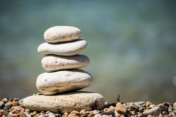 Stone pyramid on the background of the sea close-up. Calming seascape. Pebble sea coast.