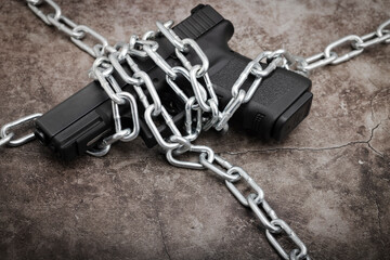 Automatic hand gun and metal chains on texture background , Gun Control and Ban concept