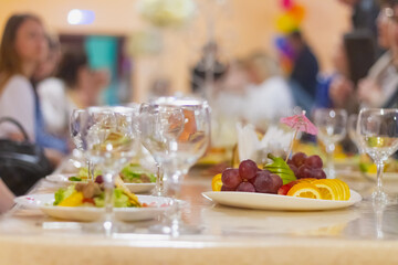 A feast in a cafe, a Russian holiday, the table is covered with glasses, Fruit, plates with salad