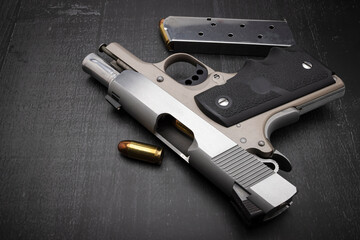 45 Semi automatic pistol hand gun with bullet magazine on wooden background , Classic gun