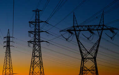 silhouettes of transmission towers at sunset.