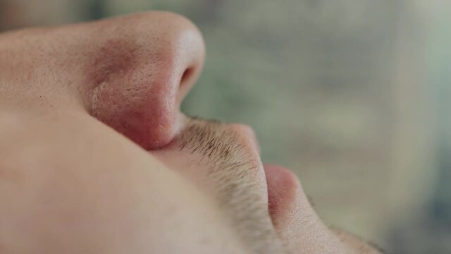 A man puts a special medical device against snoring in his sleep in his nose, macro. Problem