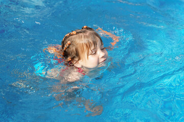 Fototapeta na wymiar caucasian child girl in sunglasses in an outdoor swimming pool on a summer day