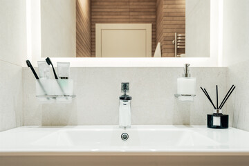Modern bathroom interior with white sink and mirror. Toothbrushes, flavoring and liquid soap - 444213144