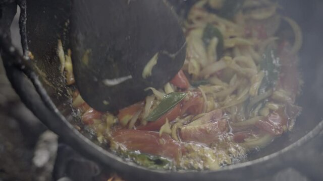 Spatula tosses stirfry vegetables on outdoor chulha fire in Manipur