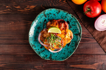 Plate with tasty tomato carpaccio on dark wooden background