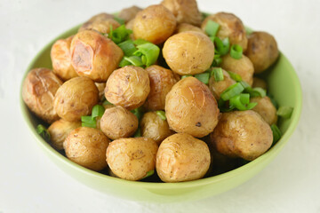 Bowl with tasty baked potato on light background