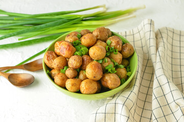 Bowl with tasty baked potato on light background