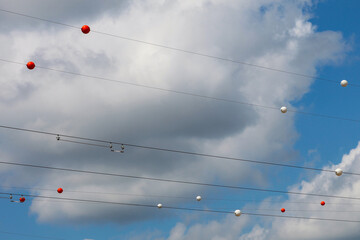 Electric wires with multi-colored balls attached to them against the background of the sky