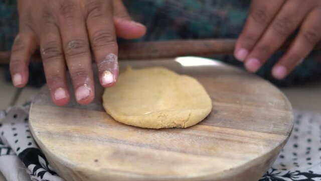 Closeup shot of hands of an Indian female making roti using the Belan roller	